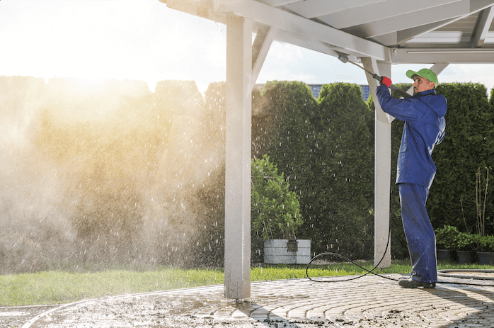 man pressure washing an awning